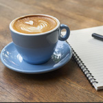 Cup of coffee next to a notebook