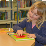 Blonde child touching a page on a book