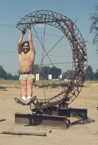 CSUN SCULPTURE UNDER CONSTRUCTION, 1975. JOHN BANKS HANGS FROM THE "C"