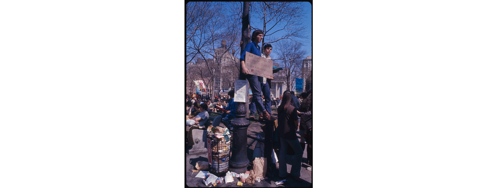 photograph of protestors with sign near overflowing trash
