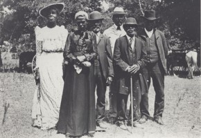 Black and white photograph of African Americans, 2 women in long dresses and 4 men in suits and hats