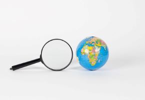 A magnifying glass set next to a globe of the world