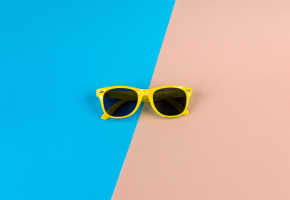 Yellow sunglasses on blue and pink background