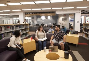 Students in the Library Learning Commons in front of the Reference Desk