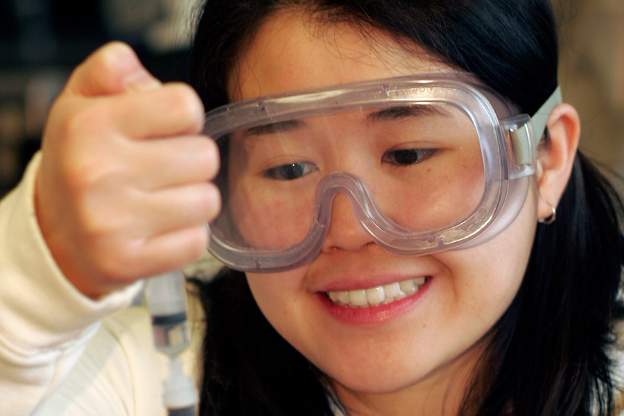 Person with goggles using a syringe in a lab