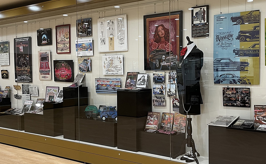 Display case at the Politics of Low & Slow Exhibition, posters, suits, magazines, model cars