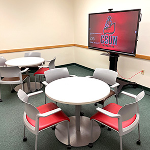 Interactive display study room, featuring two tables with four chairs each.
