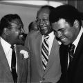 Sugar Ray Robinson, Tom Bradley, and Muhammad Ali share a happy moment as they talk together during Ali's retirement party at the Inglewood Forum. Guy Crowder Collection, 1979 ID: 91.01.GC.P.B1.08