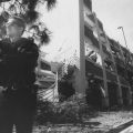 A police officer stands near a damaged parking structure on the corner of Zelzah and Plummer