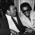 Muhammad Ali shares a laugh with Stokely Carmichael in a meeting room during a special event, 1973. Guy Crowder Collection. ID: 91.01.GC.P.B1.28