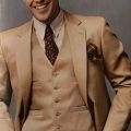 Model wearing a three piece brown suit with a striped shirt and burgundy accent, in Playboy Fashion, vol. 3-4, 1982-1983