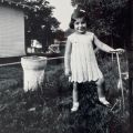 Sara Chitjian with scooter standing in the grass, ca. 1940s