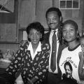 Assemblywoman Maxine Waters (left) poses in a kitchen with Jesse Jackson, and single mother Denise Calhoun during an overnight stay by Rev. Jackson at the Nickerson Gardens Housing Project in Los Angeles. Jackson later visited gang members to explore ways of avoiding gang violence. 1988. Digital ID: 11.06.GC.N35.B6.S7.42.77.04