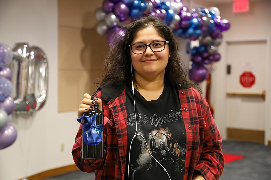 Student holding a gift bottle and looking at the camera.