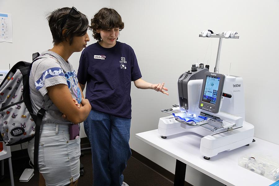 CMS student employee showing a demo of the CMS embroidery machine