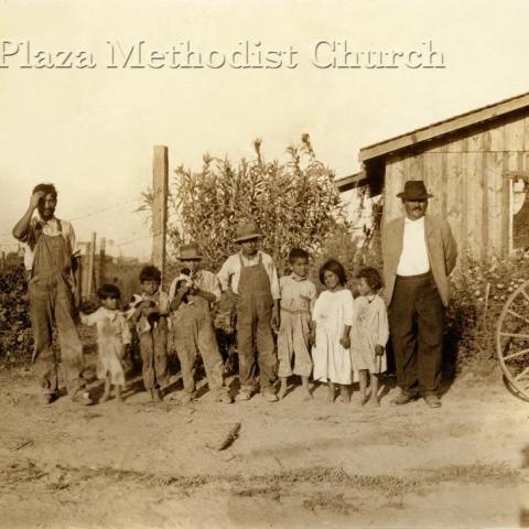 A bunch of kids and two men standing.
