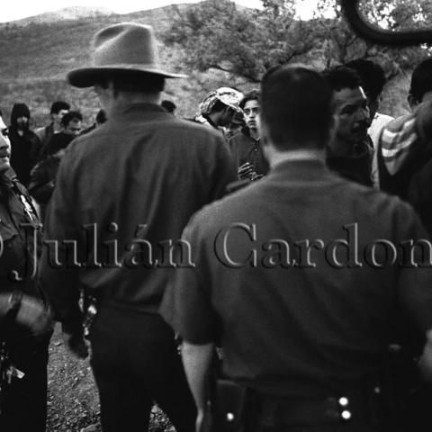 Law enforcement officials standing among a crowd.