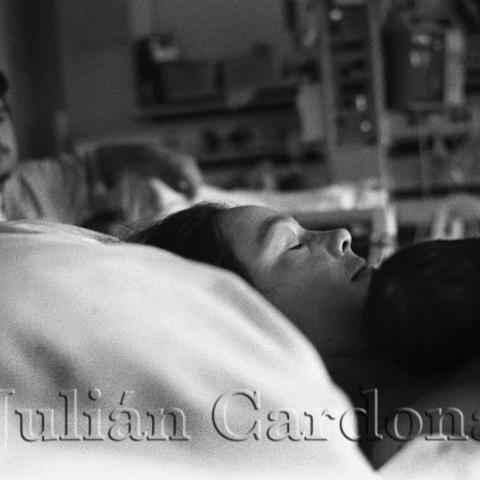A woman sleeping holding an infant.