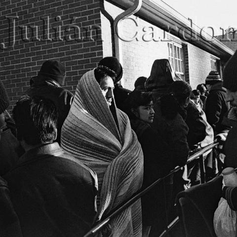 People wearing caps and blankets in the cold.
