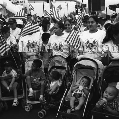 Women with strollers walking with American flags.