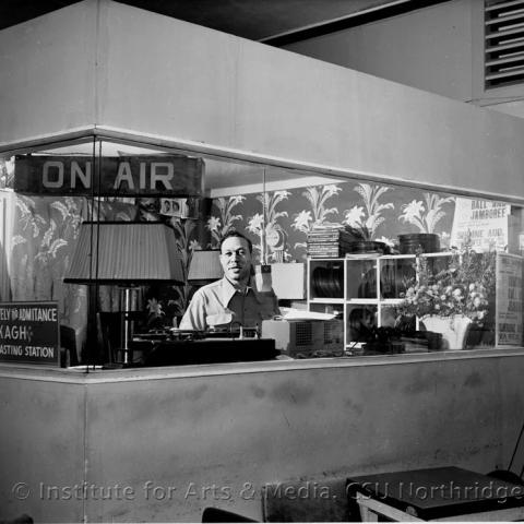 A man standing in a boardcasting station booth