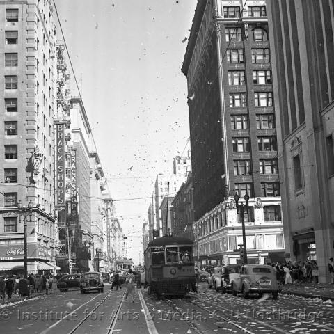 Street with car and trains with confetti in the air.