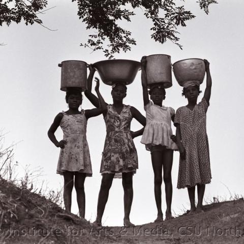 Four women carrying vessels on their heads.