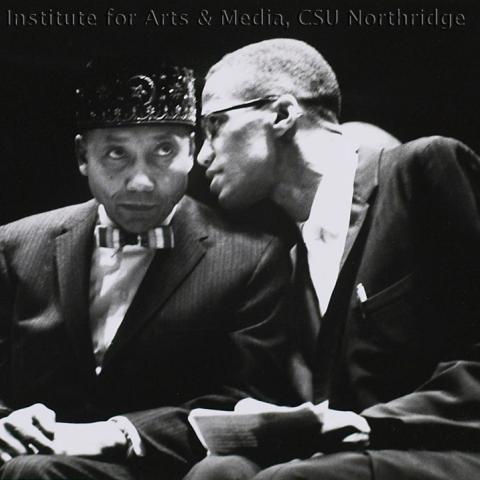 Two men speaking closely.
