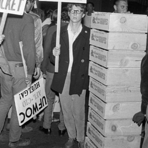 Men protesting on a sidewalk next to a stack of crates