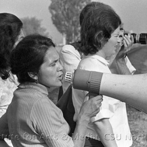 A woman speaking into a megaphone with 3 other women.