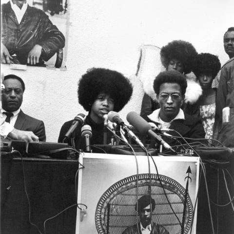 Young man with an afro speaking into microphones