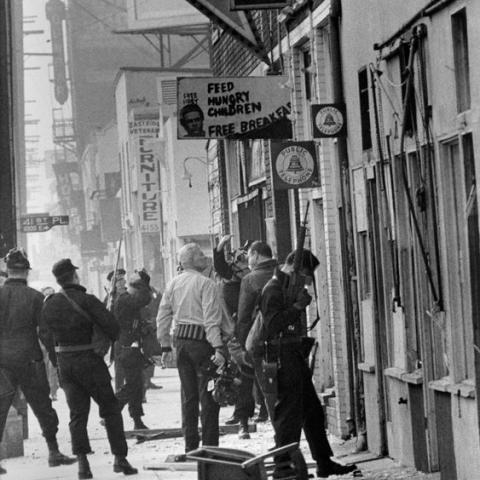 Men standing on the sidewalk with guns.
