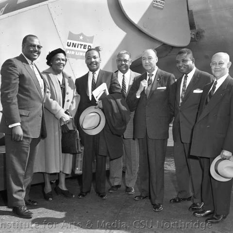 A group of people with Martin Luther King in front of united airlines airplane.