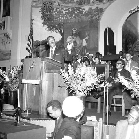 Martin Luther King on the podium giving a speech in a church.