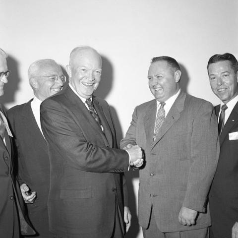 Two men shaking hands in a gathering.