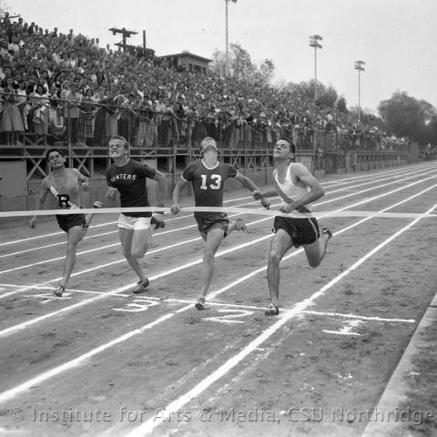 Men running on a race track near the finish line.