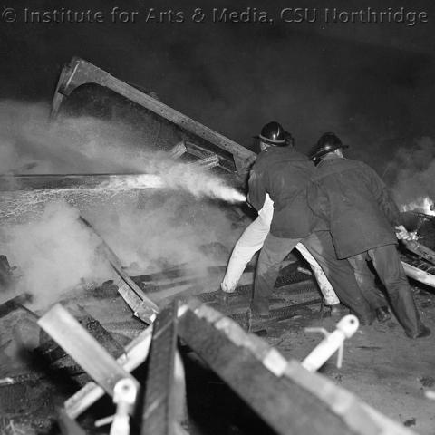 Firemen holding a large firehose.