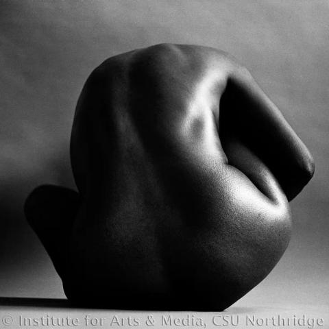 A person posing naked, curled over.