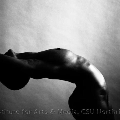 A woman posing naked, bending backwards.