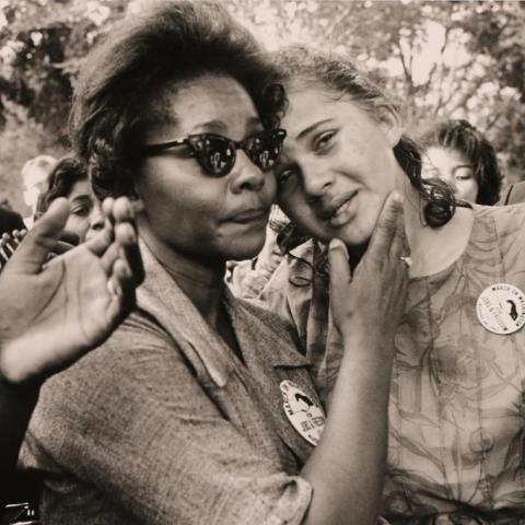 A woman consoling a girl amidst a crowd.