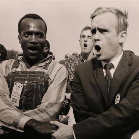 Men singing holding each other's hands.