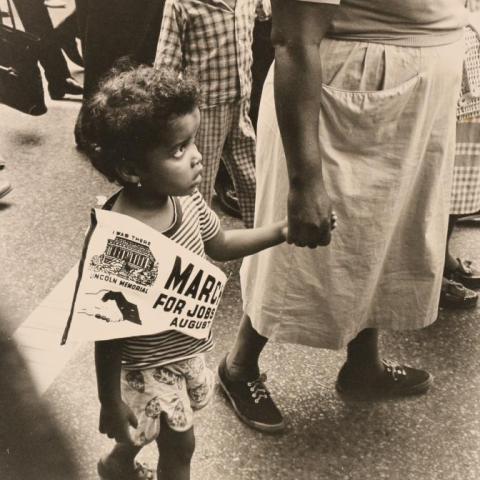 A child walking and holding an adults hand.
