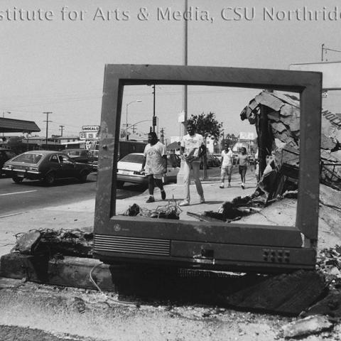 People seen through a broken TV frame.