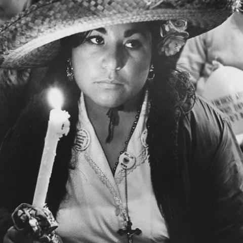 A woman holding a candle in a candlelight vigil.
