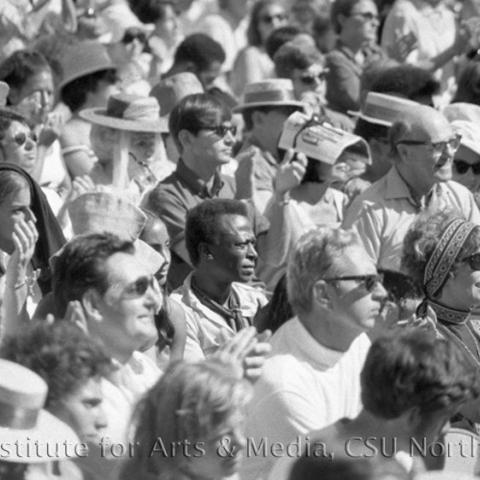 A large crowd applauding in the sun.