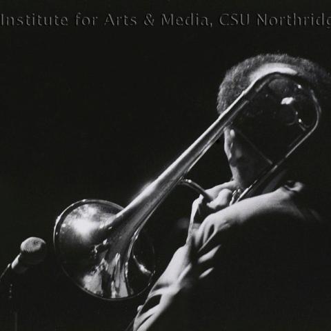 The back of a musician while he playsthe trumpet. 