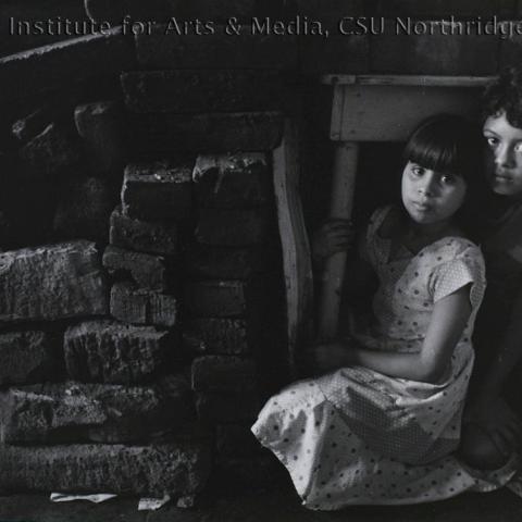 Children hiding behind a pile of bricks