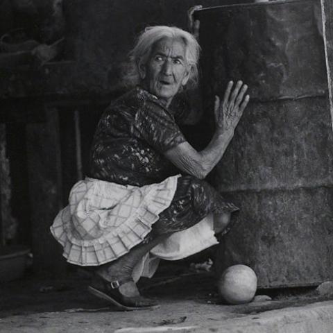 Woman taking cover next to a large metal storage drum