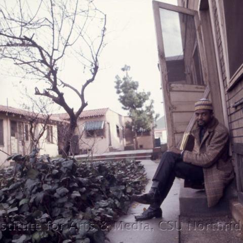 A man with a coat sitting by the door.