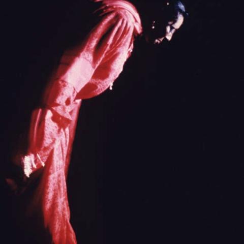 Woman in pink bowing down in spotlight.